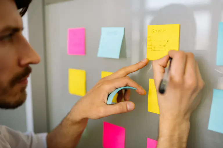 Un collaborateur devant un tableau blanc partage son expérience d’Asana en gestion de projet