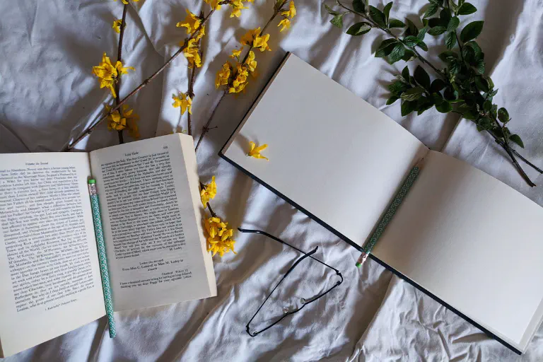 Um livro e um diário de leitura vazio pousados lado a lado.