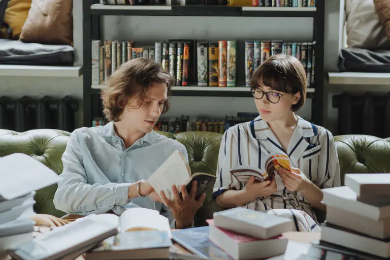 Um homem e uma mulher sentados num sofá conversam sobre livros.