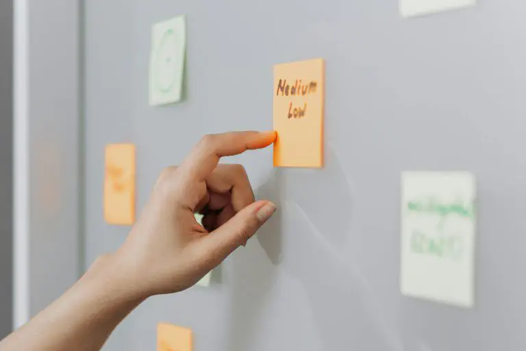 Hand zeigt auf Post-Its an einem weißen Board