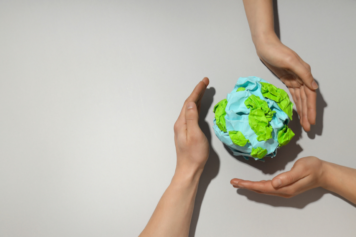 Tres manos alrededor de un globo terráqueo de papel