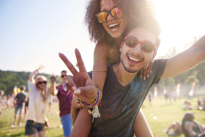 Festival packing list: Man carries woman piggyback at festival