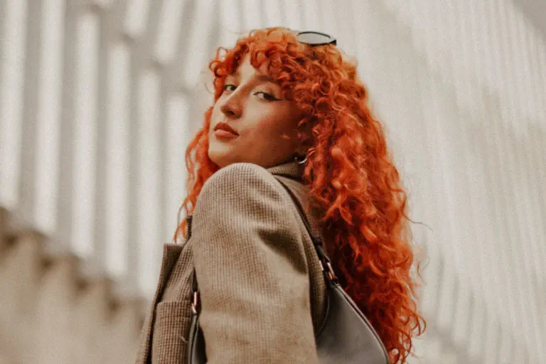 Mulher atenta às tendências da moda, com cabelo ruivo e encaracolado, posa