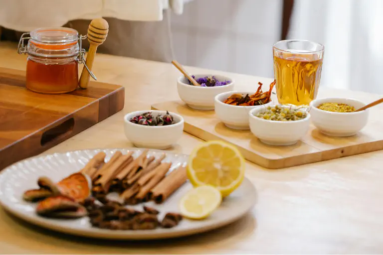 Diversos remedios caseros contra las alergias: jengibre, miel y té de hierbas sobre una mesa de madera