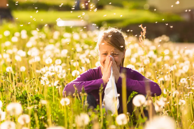 Persona en un prado en flor tapándose la nariz