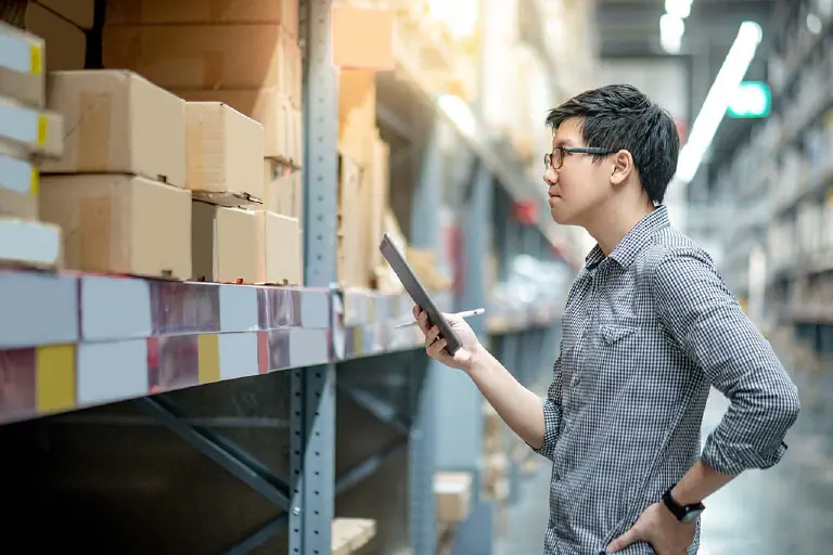 Warehouse worker takes inventory in Excel.