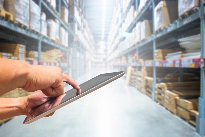 Warehouse worker uses iPad with inventory list.