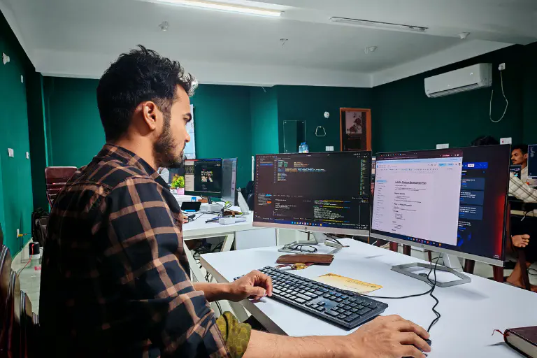 A man works at a computer on a desk.
