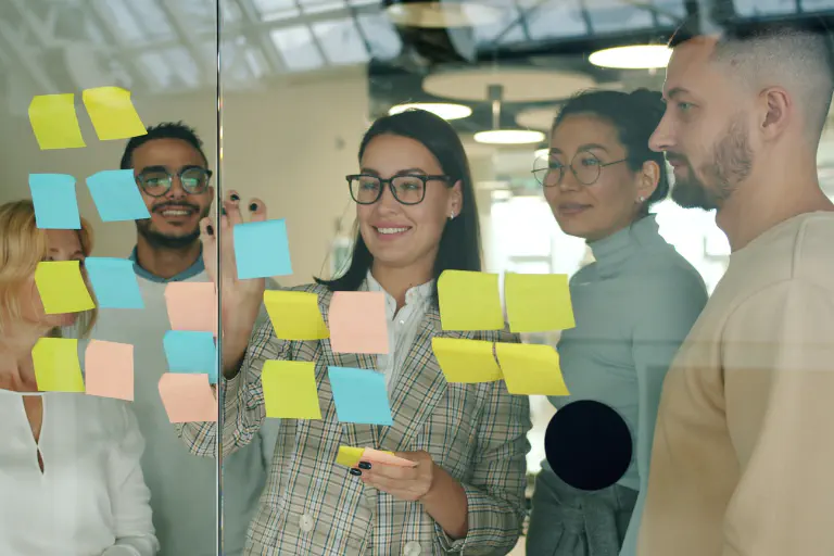 A team gathered around sticky notes on a glass surface.