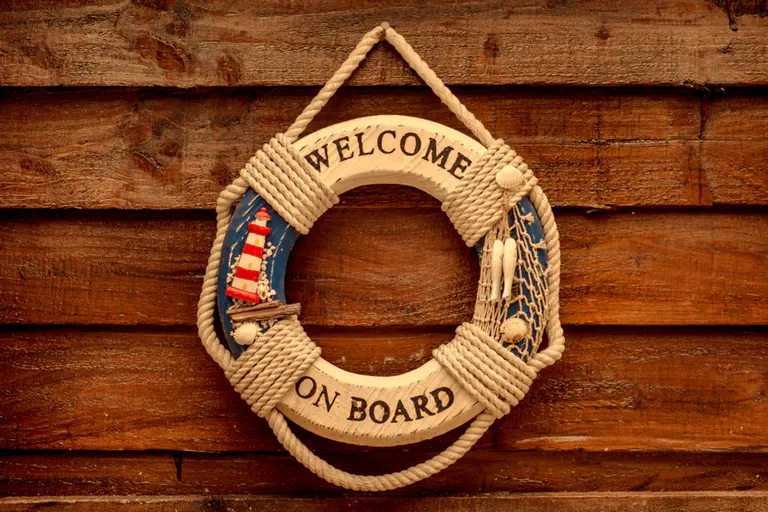 Onboarding process - The picture shows a life belt with the inscription Welcome On Board. It hangs on a plank wall