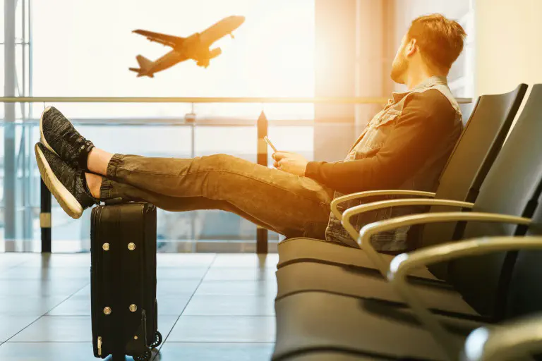 Man waiting at the airport and filling in a digital travel diary on his smartphone