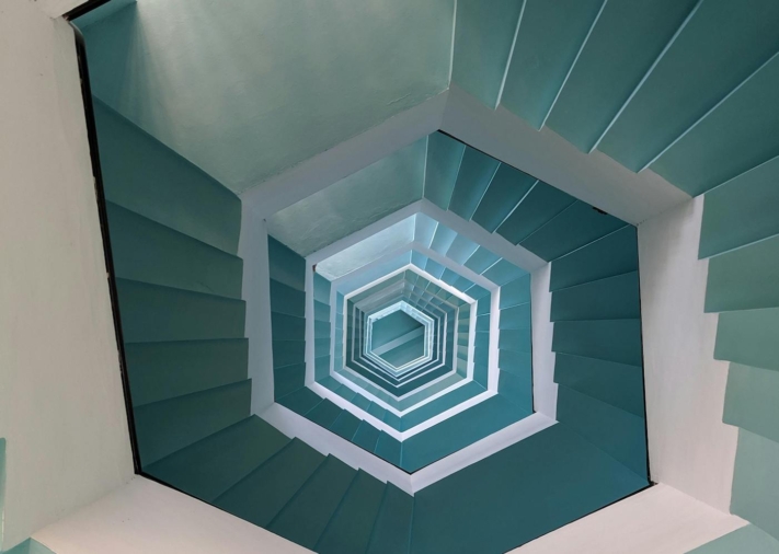 Un escalier en colimaçon en forme de nid d’abeille vu d’en haut, qui mène loin en bas